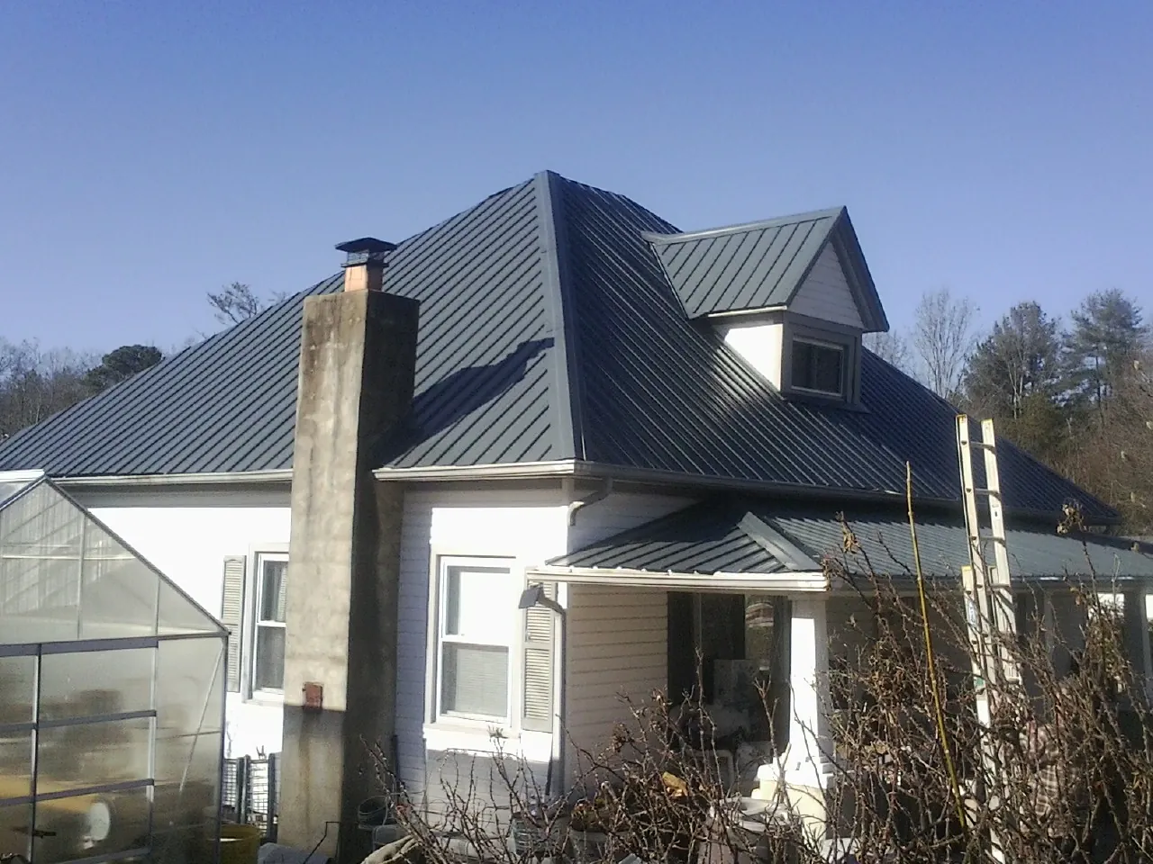 Dark blue standing seam metal roof on a white farmhouse with dormer — Slate & Tile Roof Repair by Roofing Brothers in Paul