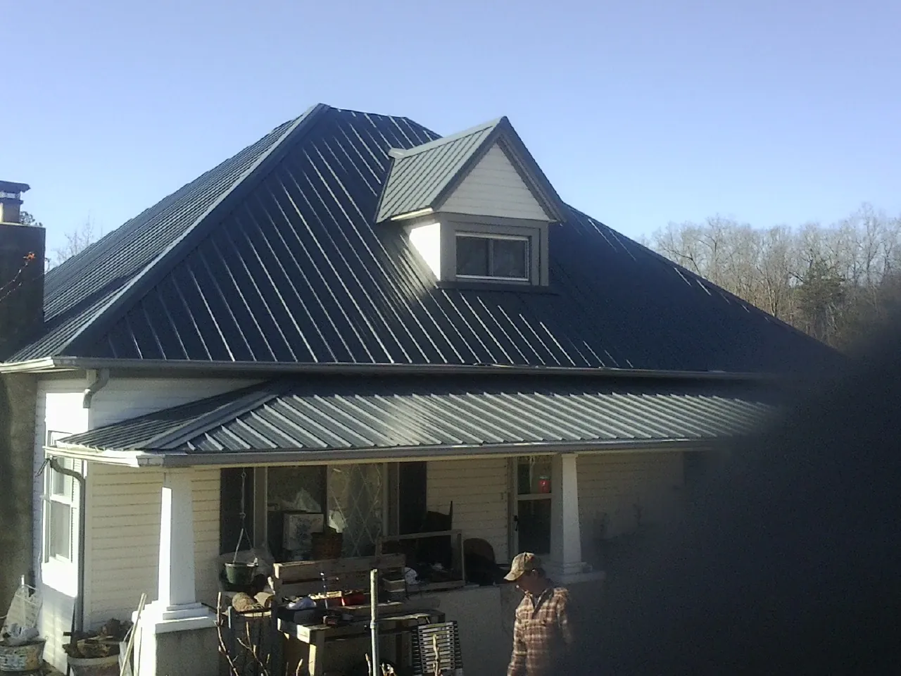 Dark blue standing seam metal roof with a dormer above a front porch in Paul