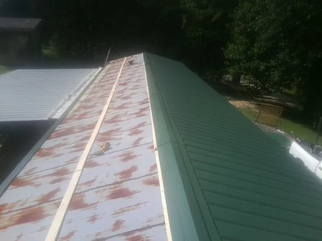 Old rusted panels beside newly installed green metal roofing — Wind Damage Roof Repair by Roofing Brothers in Paul