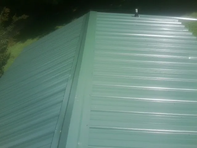 New green metal panels meeting at the ridge of a roof — Flat Roof Repair work by our crew in Paul