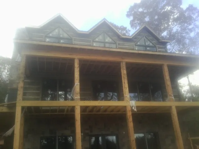 Dormers and porch framing on a large log home under construction — Roof Coating work by our crew in Paul