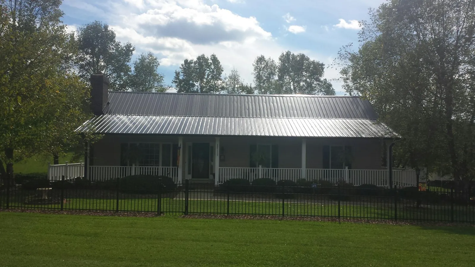 Gray metal roof on a brick ranch with a full width front porch — Gutter Guard Installation work by our crew in Paul