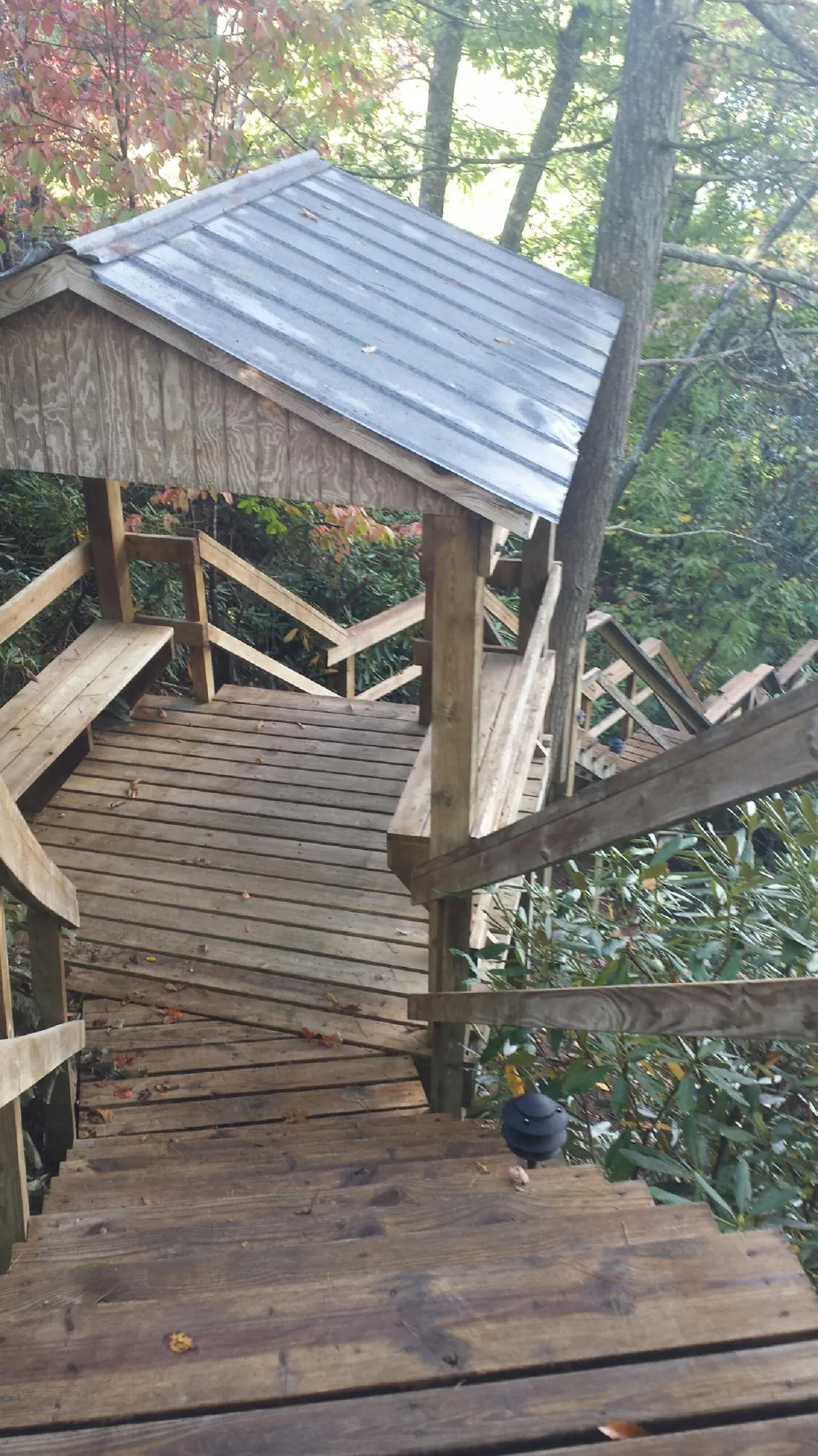 Metal roofed shelter over wooden steps on a wooded walkway — Skylight Repair & Installation work by our crew in Paul
