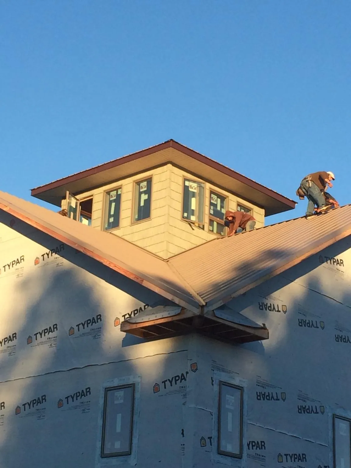 Roofers working around a rooftop cupola on a new metal roof at sunset — Roof Waterproofing in Paul by Roofing Brothers
